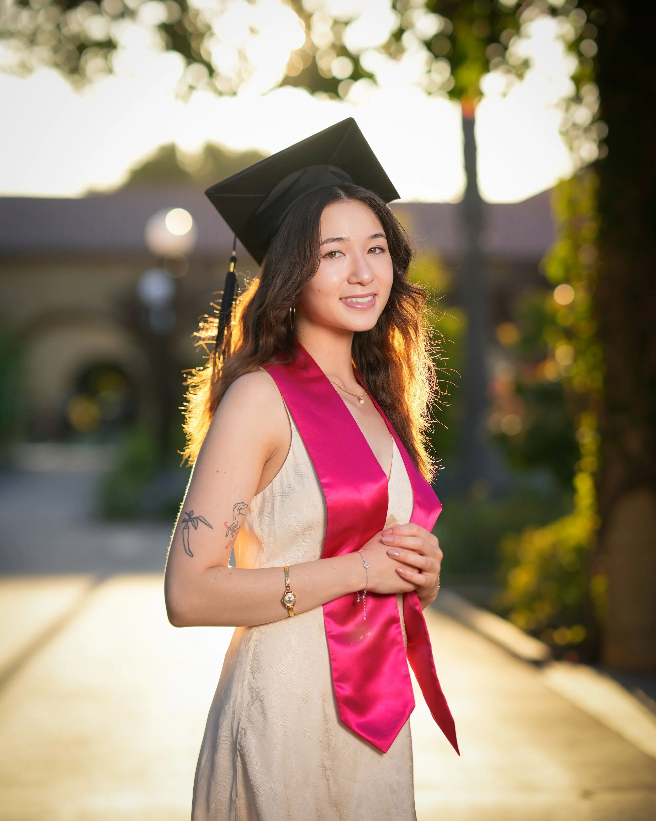 Graduation portrait with a pink stole on Palm Drive in Stanford, California